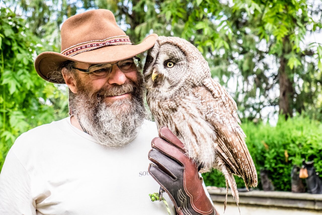 Richard Grossman smiling beside a great grey owl